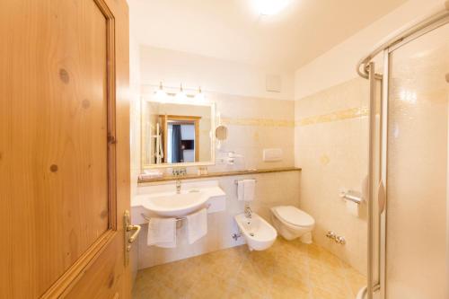 a bathroom with a sink and a toilet and a mirror at Hotel Schlosswirt in Schenna
