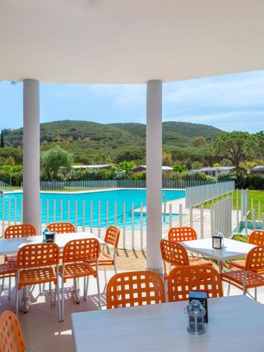 a patio with tables and chairs and a pool at Camping Lacona Pineta in Capoliveri