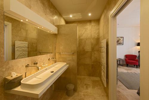 a bathroom with a sink and a red chair at The Snop House in Senglea