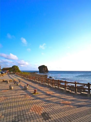 a row of benches on a beach next to the water at Jing Guan Hotel in Eluan