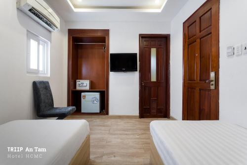 a room with two beds and a chair and a door at Mays Hotel- Ben Thanh in Ho Chi Minh City