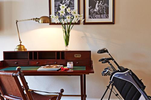 a desk with a lamp and a vase of flowers at Kokkedal Slot Copenhagen in Hørsholm