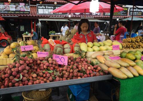 Eine Frau steht hinter einem Obststand auf einem Markt. in der Unterkunft Villa Amber in Laem Set Beach
