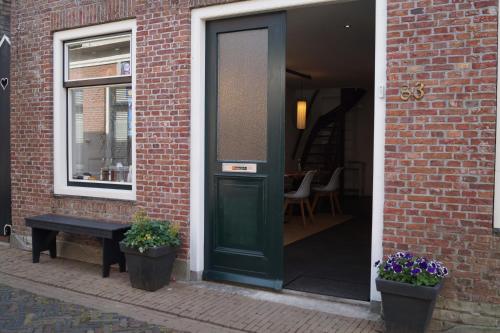 a green door on a brick building with two potted plants at Mid83 in Woudsend