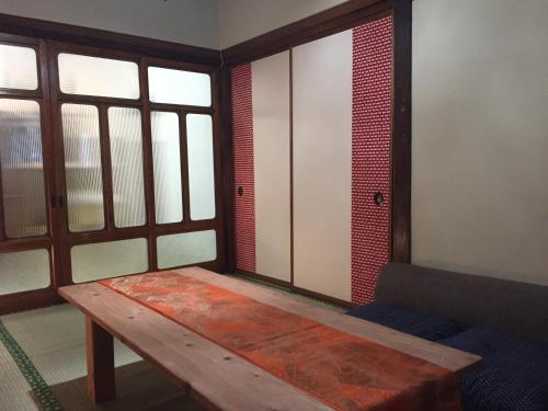 um quarto com uma mesa de madeira num quarto com janelas em 宿家STARY越中 izumicho em Toyama
