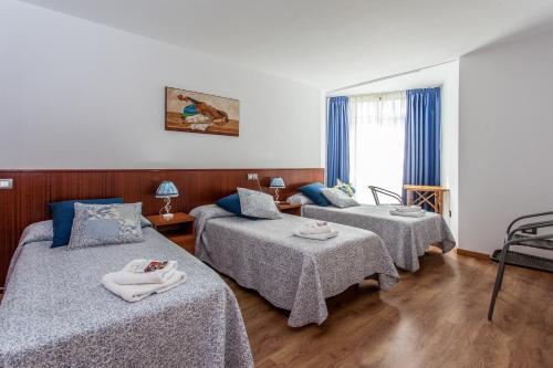 a room with three beds with towels on them at Pensión O Castelo in Palas de Rei