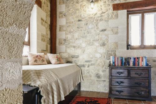 1 dormitorio con pared de piedra, cama y vestidor en Ariadni Stone House with private pool, en Kolimvárion