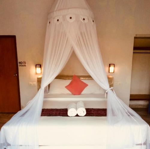 a bedroom with a canopy bed with two slippers at Naradas Mushroom Beach in Nusa Lembongan