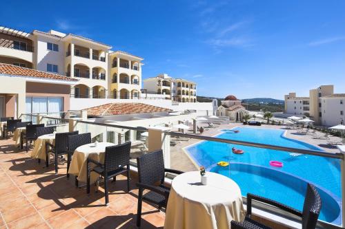 eine Terrasse mit Tischen und Stühlen neben einem Pool in der Unterkunft Club St. George in Paphos City