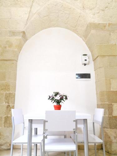 a white table with white chairs and a vase with flowers at CASA TIPICA indipendente in Carpignano Salentino