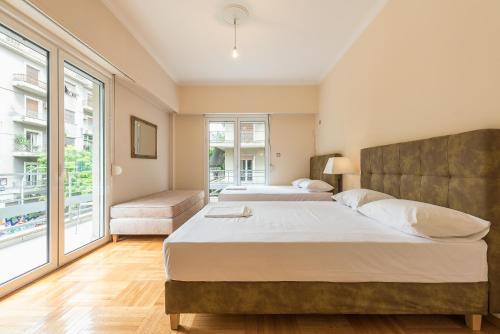 1 Schlafzimmer mit 2 Betten und einem großen Fenster in der Unterkunft Victoria Familia Apartments in Athen