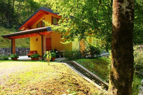 una piccola casa gialla in mezzo a un cortile di Casa Vela a Ledro