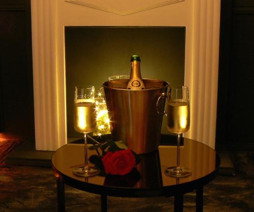 a bottle of champagne in a bucket on a table with two candles at Loveroom Lovegite Le Cocon Enchanteur in Plélan-le-Grand