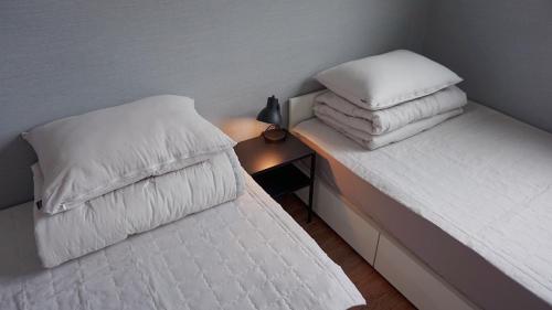 1 dormitorio con 2 camas con almohadas blancas en Sh Guesthouse en Chuncheon