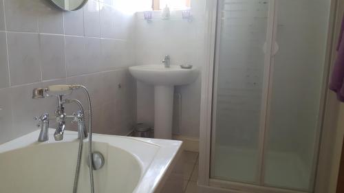 a bathroom with a sink and a tub and a shower at Le Patronage in Bazoges-en-Pareds