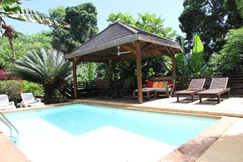 a swimming pool with a gazebo and chairs at Villa Maora in Kangani