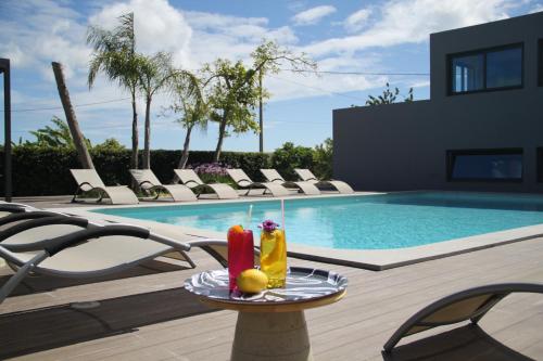 a table with two drinks on it next to a swimming pool at Villas Marim in Olhão