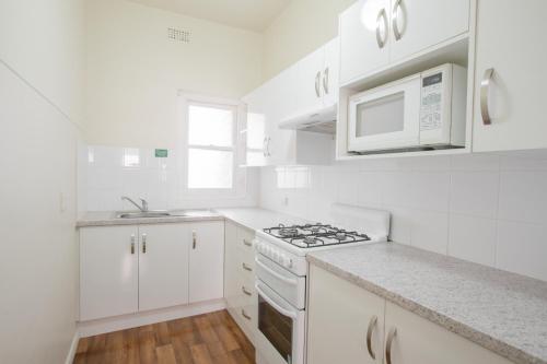 a white kitchen with a stove and a microwave at Greenways Apartments in Adelaide
