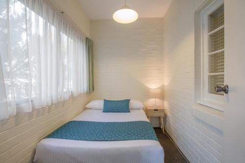 a small bedroom with a bed and a window at Greenways Apartments in Adelaide