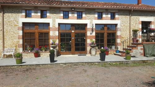 a building with doors and potted plants in front of it at Le Patronage in Bazoges-en-Pareds