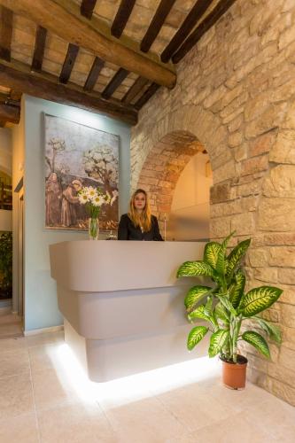 a woman standing behind a counter in a stone wall at Hotel Il Duomo in Assisi
