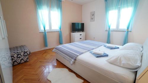 a bedroom with a bed with blue curtains and a television at Apartment Ana in Vinjerac