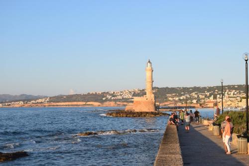 a group of people walking along a pier with a lighthouse at Sofias Home in Chania