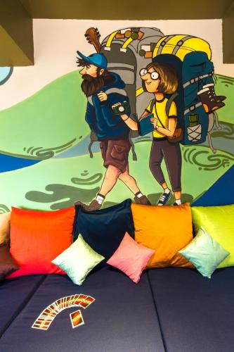 a room with a mural of two people walking toward a bed at Zostel Plus Panchgani in Panchgani