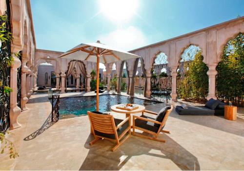 a patio with a table and chairs and an umbrella at Palais Namaskar in Marrakech