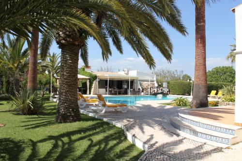 a villa with a swimming pool and palm trees at Quinta dos Oliveiras in Carvoeiro