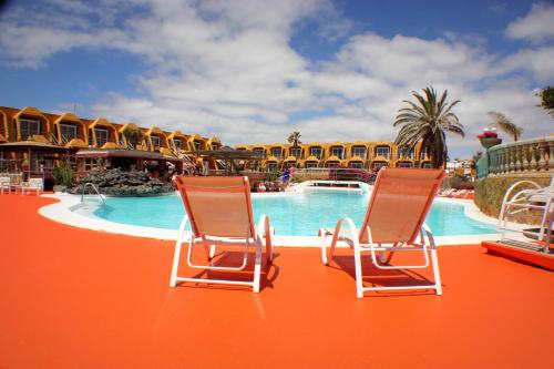 two chairs sitting in front of a pool at a resort at Aparthotel la Piramide in Costa de Antigua