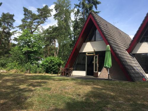 a small house with a pitched roof with a patio at 't Vosseven vakantiehuizen in Stramproy