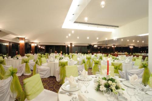 a banquet hall with white tables and green chairs at Burcman Hotel in Bursa