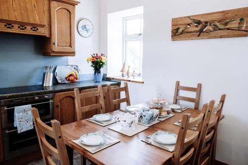 uma cozinha com uma mesa de madeira com cadeiras à volta em Stockman's Cottage em Kirkcudbright
