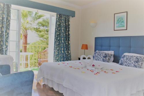 a bedroom with a bed with a white blanket and a window at Quinta dos Oliveiras in Carvoeiro