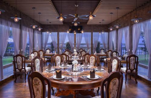 a dining room with a table and chairs and windows at LCS Hotel & Apartment in Phnom Penh
