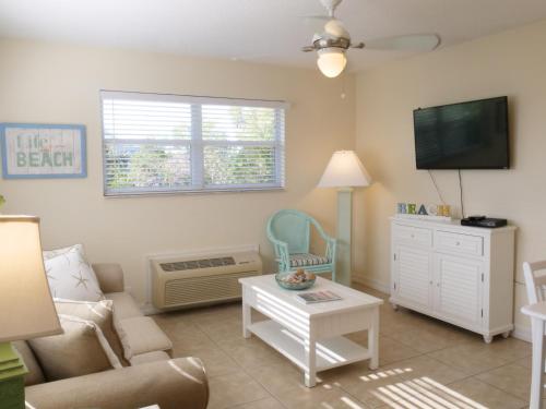 a living room filled with furniture and a tv at The Sea Spray Resort in Siesta Key