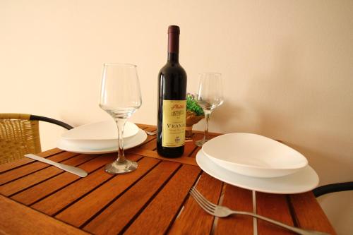a bottle of wine and two glasses on a wooden table at Apartments Astoria HN in Herceg-Novi