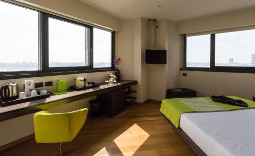 a bedroom with a bed and a desk and windows at Best Western Plus The Hub Hotel in Milan