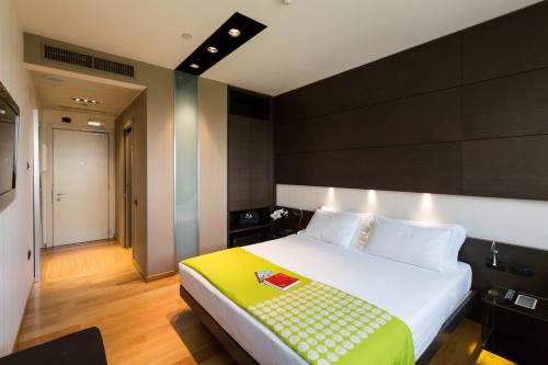 a bedroom with a large white bed with a yellow blanket at Best Western Plus The Hub Hotel in Milan