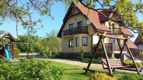 a house with a playground in front of it at Gospodarstwo Agroturystyczne Rowerowa Przystań "Jankesówka" in Lidzbark Warmiński
