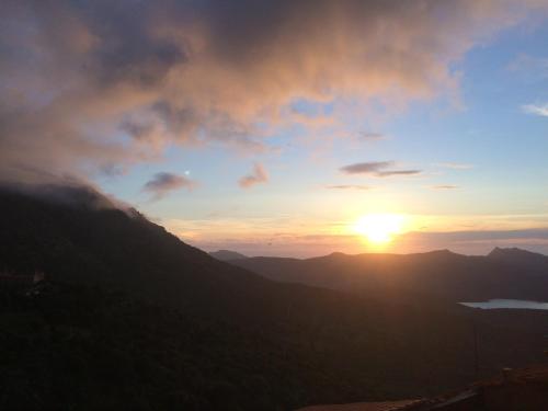 a sunset in the mountains with the sun in the sky at A Spelunca in Speloncato