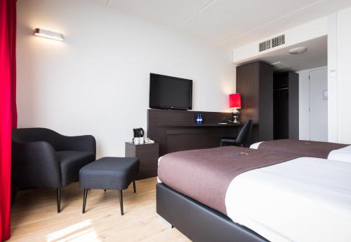 um quarto de hotel com uma cama e uma televisão de ecrã plano em Bastion Hotel Almere em Almere