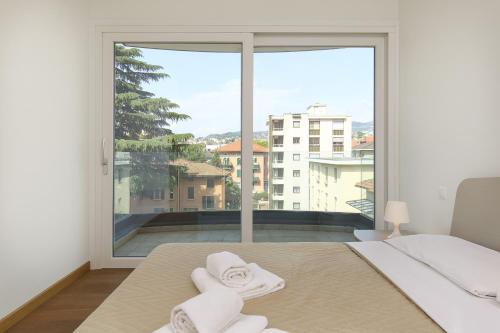 a bedroom with a large window with towels on a bed at Roggia Apartments by Quokka 360 - central flats with parking space in Lugano