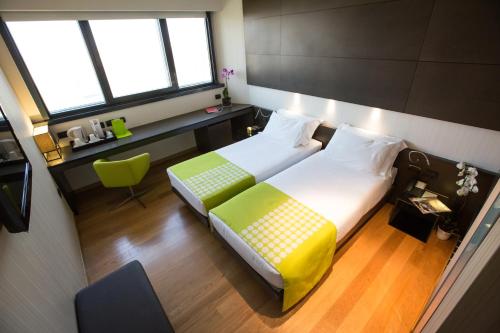 a bedroom with a bed and a desk and two windows at Best Western Plus The Hub Hotel in Milan