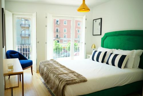 a bedroom with a large bed and a blue chair at Casas da Baixa - Vila Intendente in Lisbon