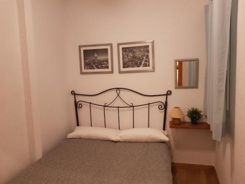 マラガにあるJulias Apartmentの壁に2枚の写真が飾られた部屋のベッド1台分です。