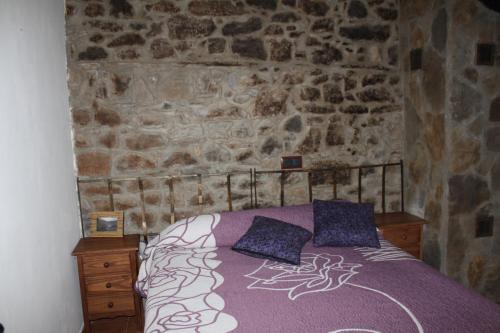 1 dormitorio con cama y pared de piedra en Casa Rural Las Machorras I y II, en Bárcenas