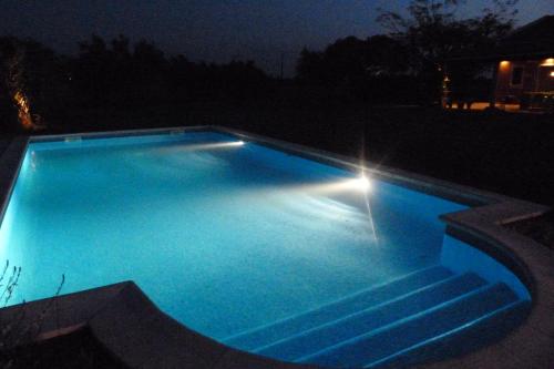 a blue swimming pool at night with a light at Quinta dos doze Sobreiros - Quarto Sol in Ferreira do Alentejo