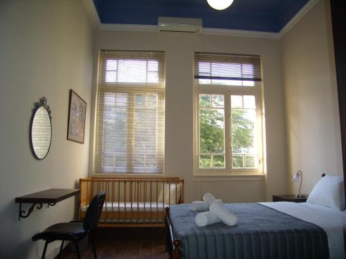 una camera con un letto e una sedia e due finestre di Neoclassical Glamour a Chania